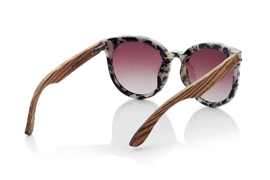 Wood eyewear of Walnut INTHIRA. INTHIRA sunglasses are the perfect complement to any feminine look. Her frontal frame in tortoiseshell shades of black, gray and cream and her rounded shape make her stand out. The lenses are mounted overexposed in the frame, giving it a very modern and attractive look. The wide temples are in grained walnut contrasting with the frame. This model is available in several lens colors, so you can choose the one that best suits your tastes and needs. With INTHIRA sunglasses, you will not go unnoticed. Front measurement approx: 142x55mmApprox front measurement: 142x55mm for Wholesale & Retail | Root Sunglasses® 